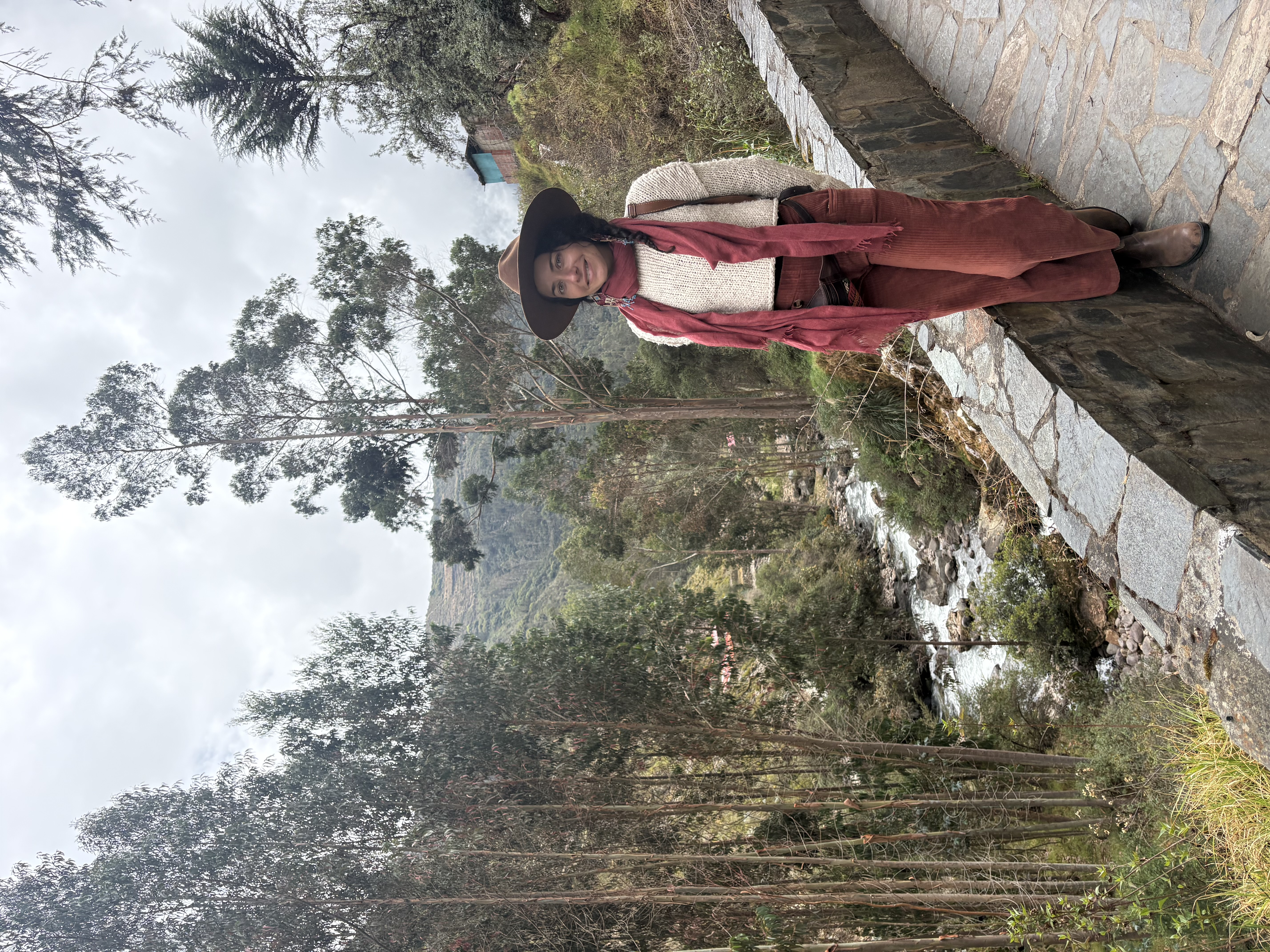 Priscilla standing beside a wooded mountain stream